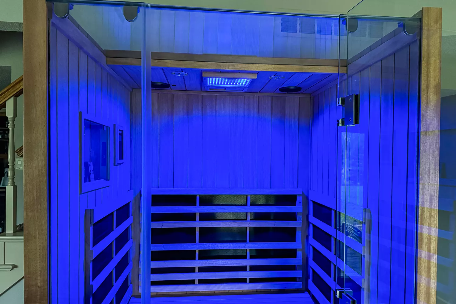 Interior of a two-person infrared sauna illuminated with soothing blue LED chromotherapy lighting.