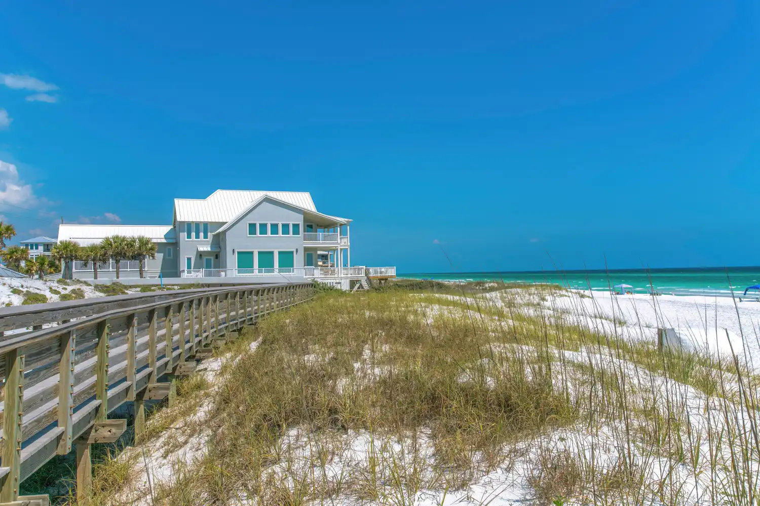 A wooden boardwalk leading toward traditional beach houses in Seaside Florida.