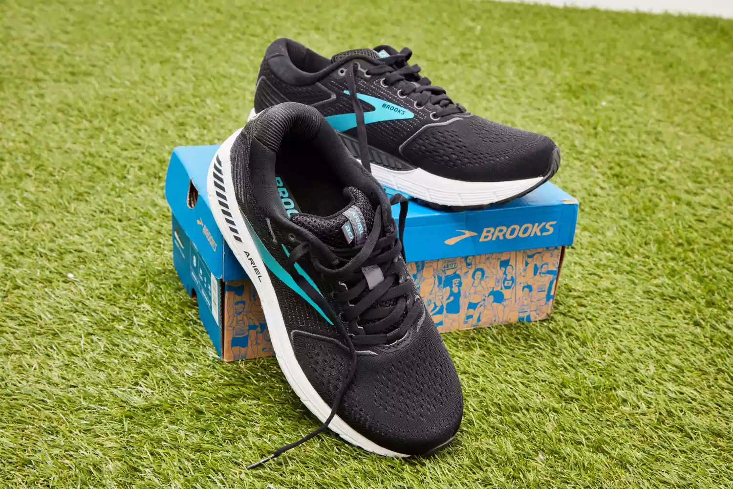Black Brooks Ariel 20 running shoes on a blue box and green turf.