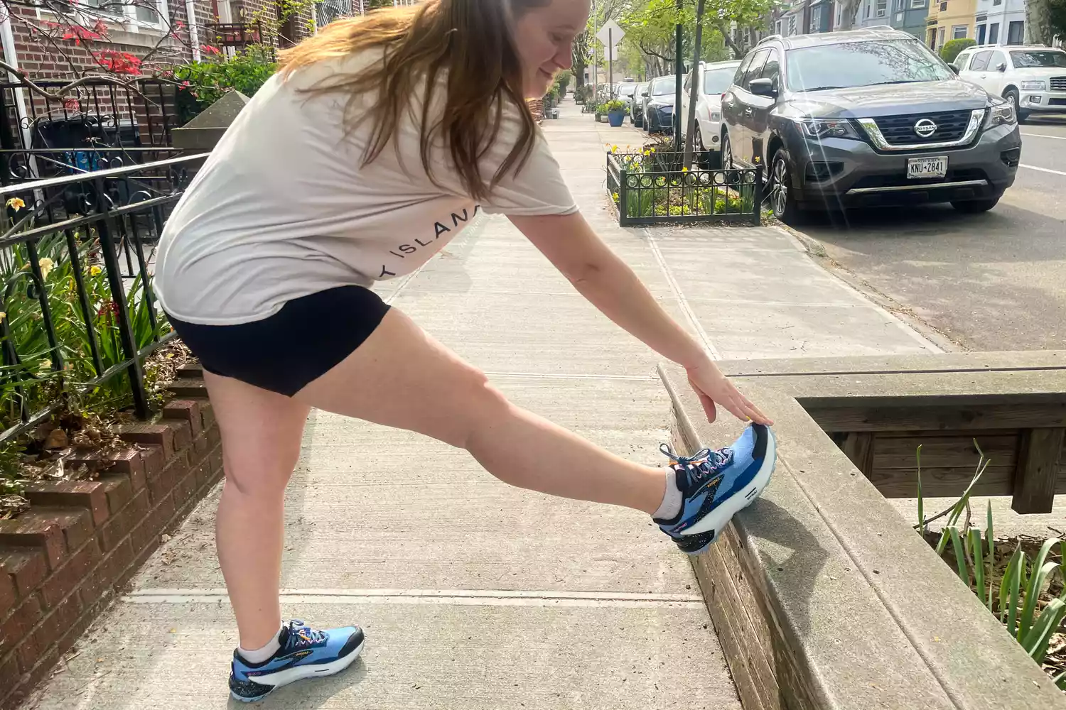 A runner performing a hamstring stretch on a ledge before starting a workout.