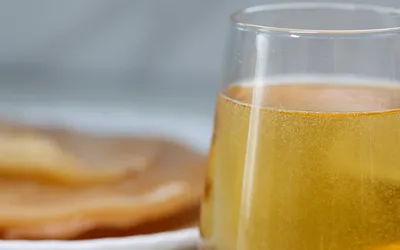 A close-up of bubbly golden kombucha in a glass with a SCOBY visible, highlighting the probiotic culture.