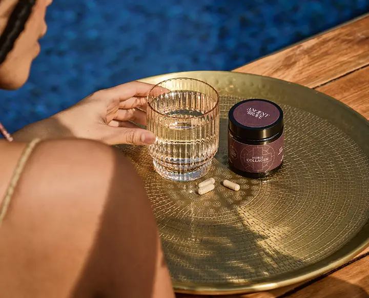 A close-up of healthy, hydrated skin alongside a glass of water containing dissolved marine collagen.