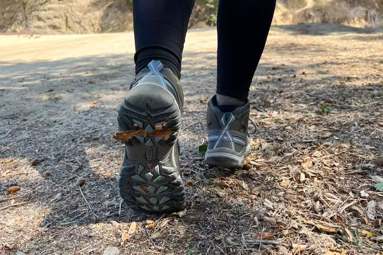 Close-up of KEEN Targhee III Mid Waterproof boots being used on a leaf-strewn forest trail.