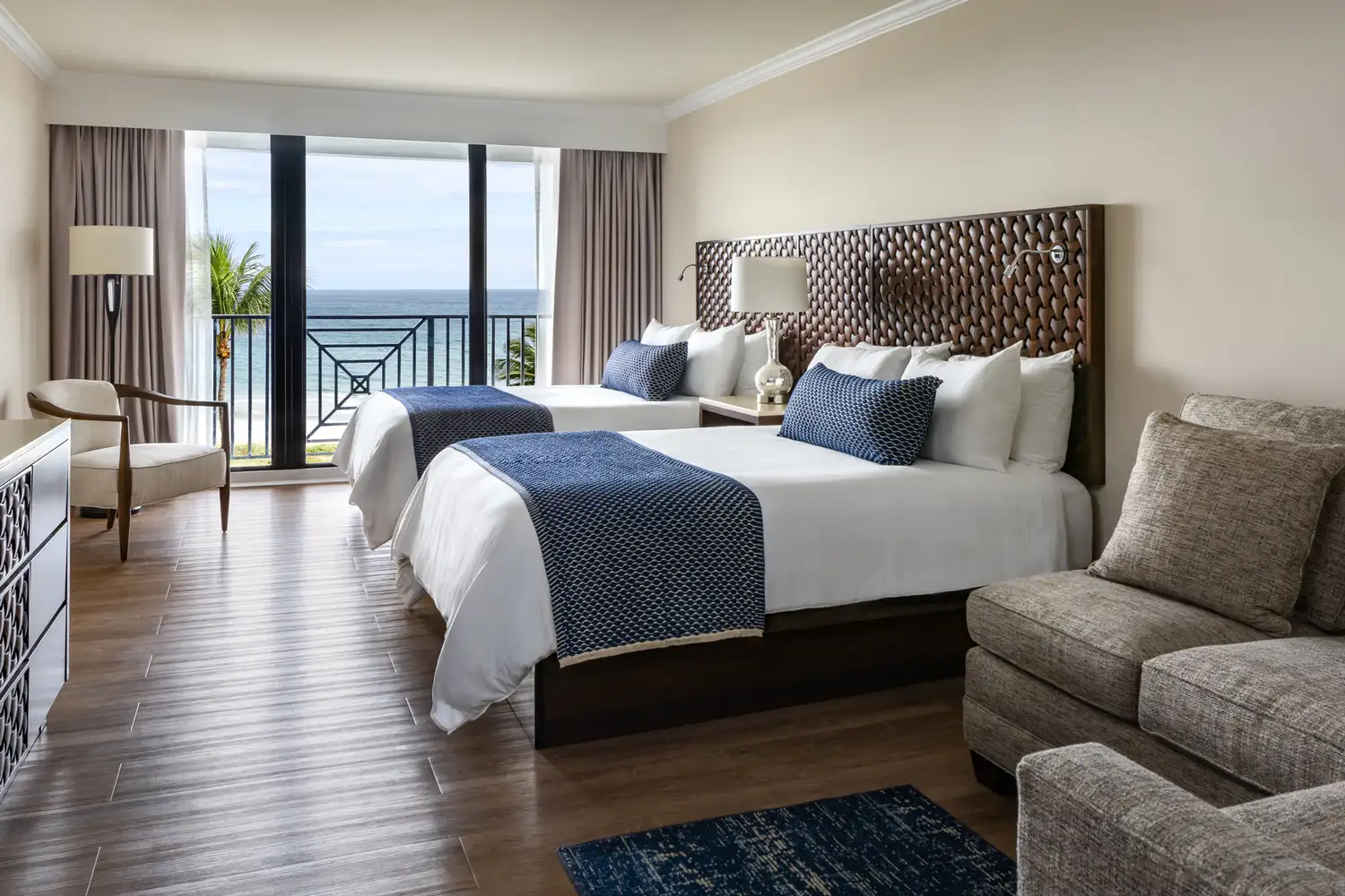 A luxury hotel room at Opal Grand Resort with a view of the ocean through a balcony window.