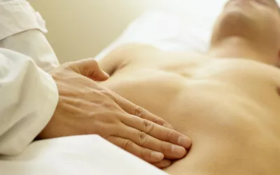 A doctor performing an abdominal palpation on a patient.