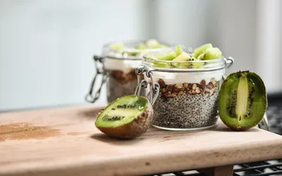 Two jars of chia seed pudding with yogurt and kiwi slices.