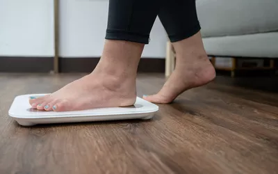 Close-up of a person's feet standing on a digital scale at home.
