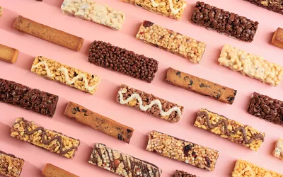 A variety of processed snack bars on a pink background.