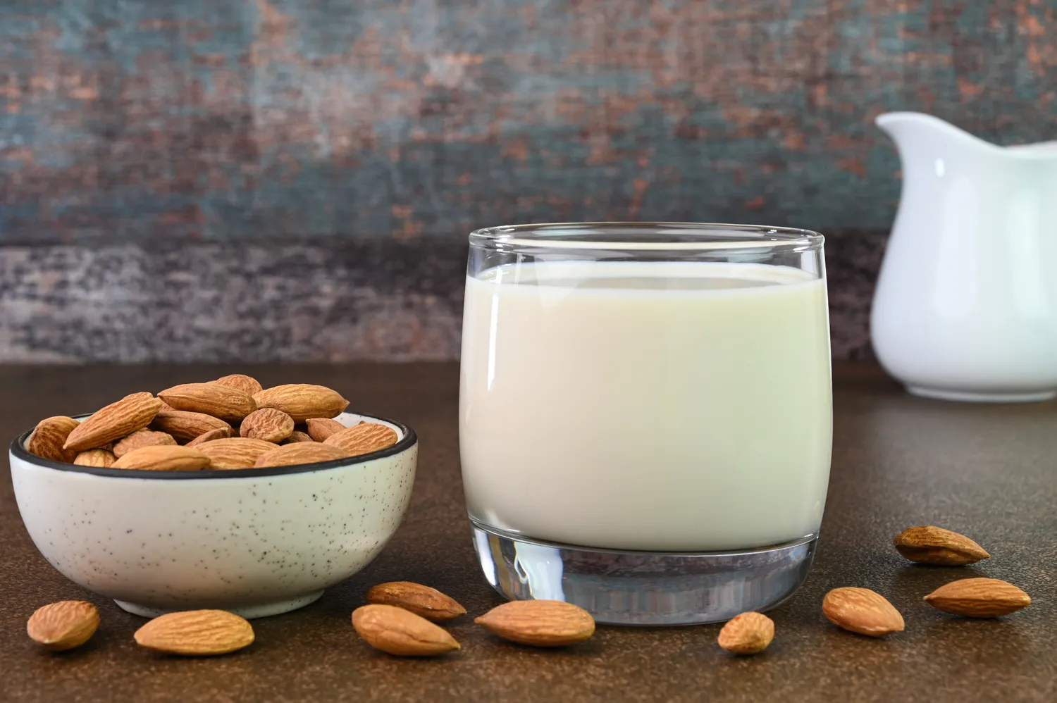 Almond milk in a bottle next to a bowl of whole almonds.