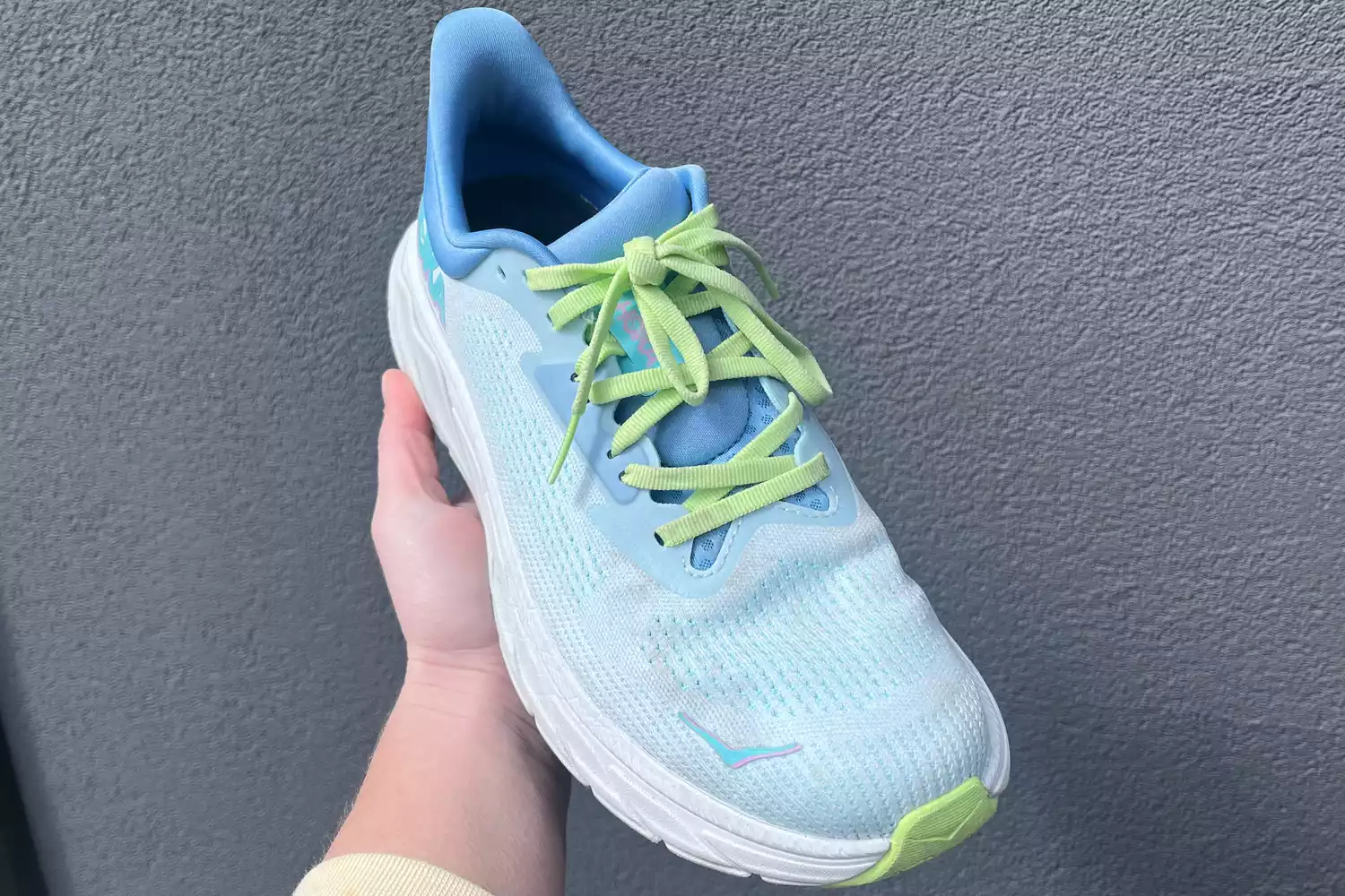 A hand holding the Hoka Arahi stability shoe, highlighting its streamlined design.