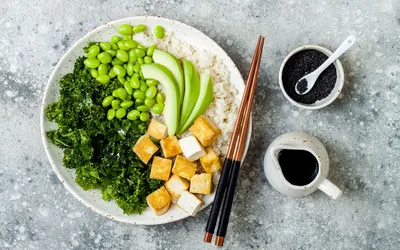 A vibrant bowl with tofu, avocado, kale, and edamame.