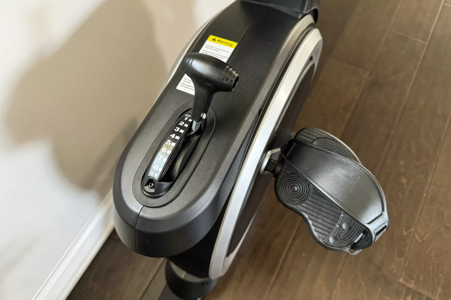 Close-up of a recumbent bike's manual resistance adjustment lever showing levels 1 to 8.