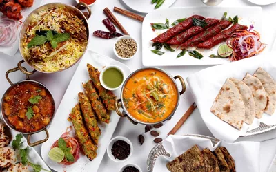 A variety of spicy and rich Indian dishes including curry and naan, which may act as food triggers for IBS symptoms.