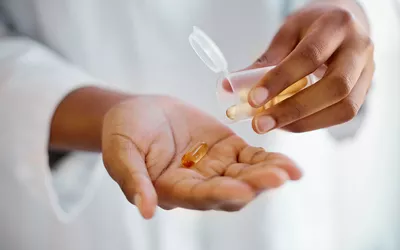 A healthcare professional dispensing a supplement capsule, representing medical wellness support.