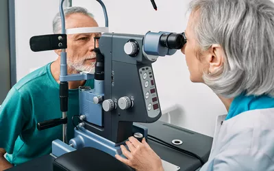 An optometrist using a slit lamp to perform a detailed eye examination on a patient.
