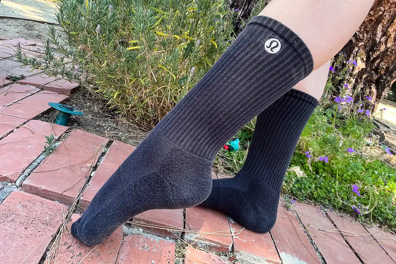 A person wearing Lululemon socks standing in a lush garden setting, suggesting wellness and daily use.