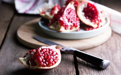 Freshly sliced pomegranates on a wooden board, representing antioxidant-rich food sources.