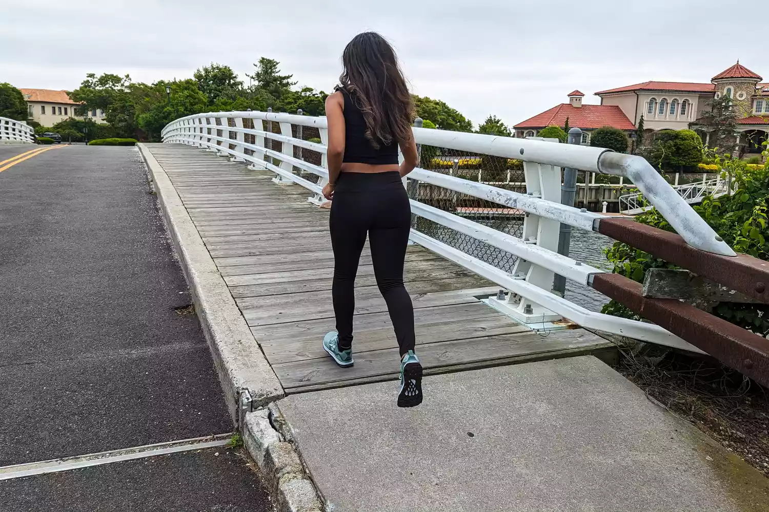 A woman in athletic wear jogging/walking across a bridge during a fitness test.
