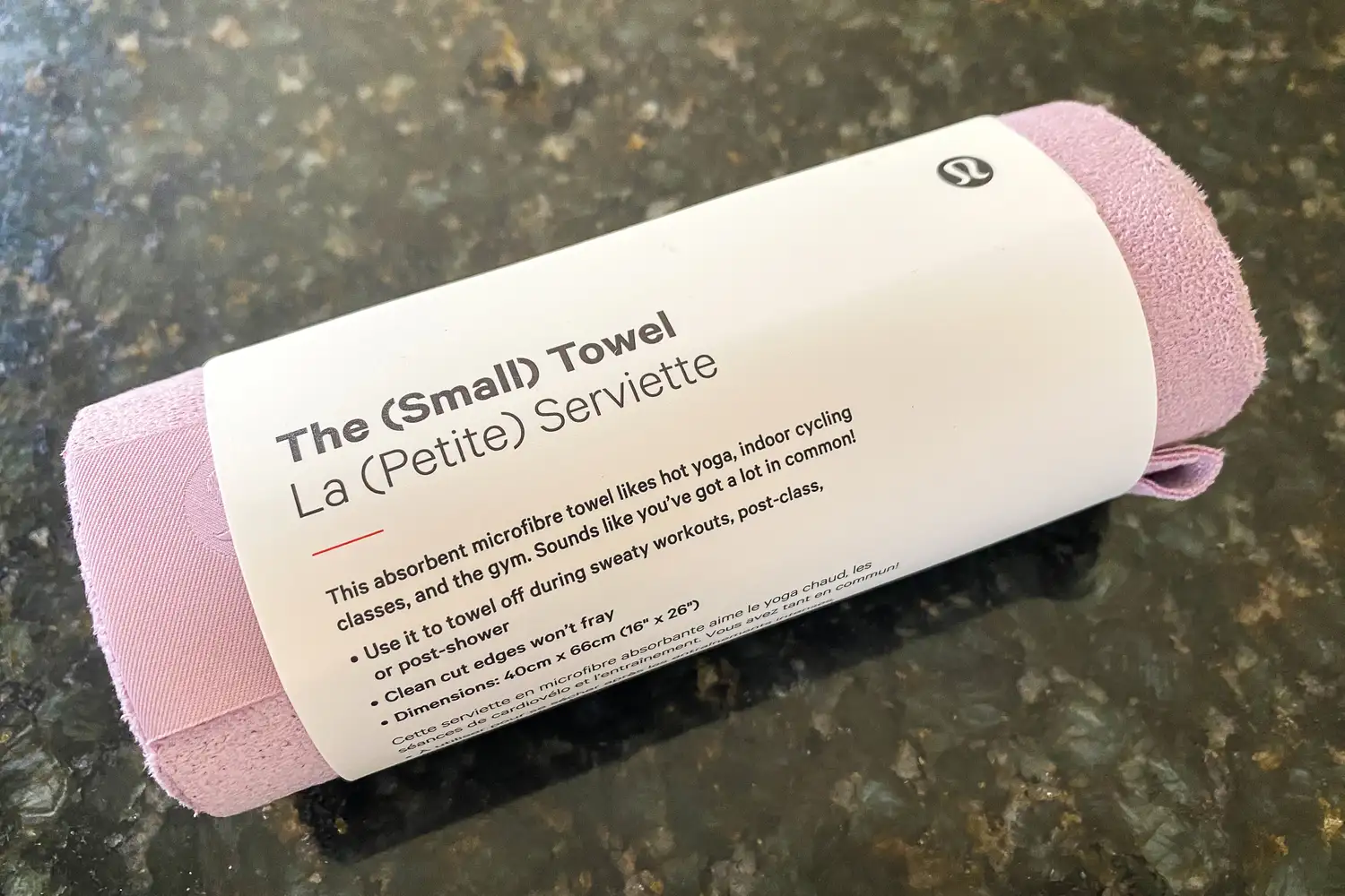 A rolled-up pink Lululemon microfiber towel designed for hot yoga and gym use.