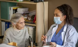A healthcare professional consulting with an elderly patient during a clinical visit.