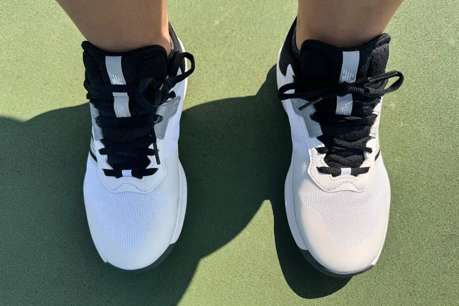 Overhead view of a player wearing New Balance 696v6 sneakers on a green court.