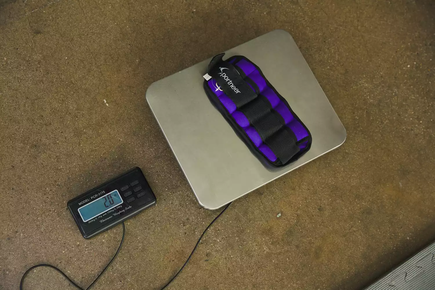 A purple Sportneer ankle weight on a digital scale showing exactly 2.0 lbs.