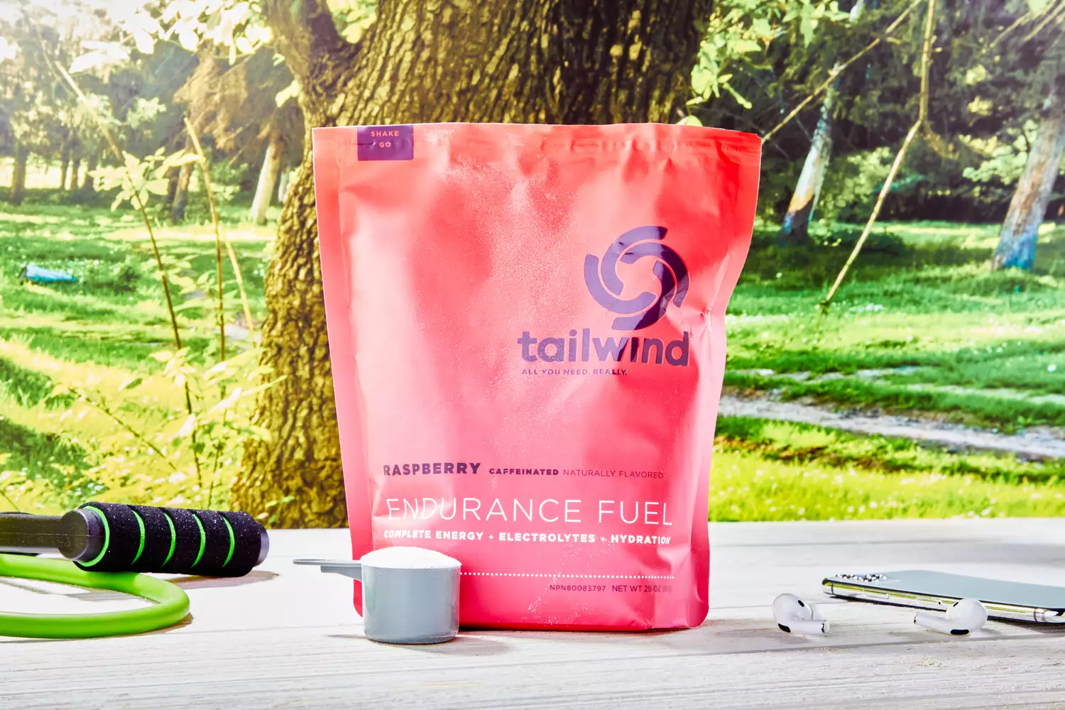 A bag of Tailwind Raspberry Caffeinated Endurance Fuel on a table with a jump rope and earbuds.