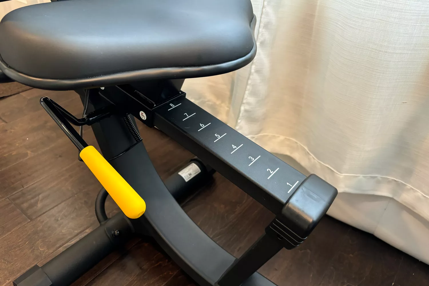 Close-up of an adjustable seat lever on a recumbent exercise bike frame.
