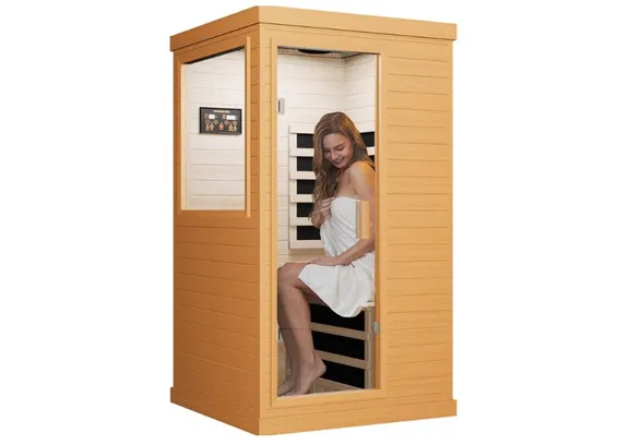 A woman with her eyes closed relaxes inside the warm glow of a wooden infrared sauna.
