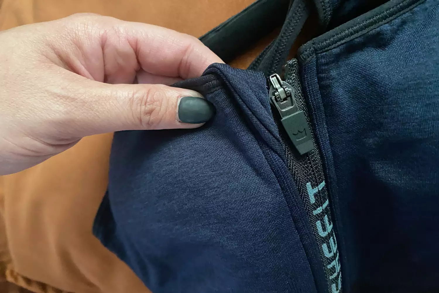 Close-up of a hand adjusting a SheFit sports bra's front zipper.