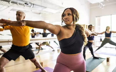 A group of adults practicing yoga in a bright studio setting.