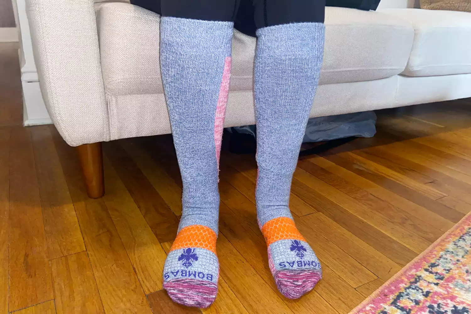 A person wearing patterned Bombas compression socks while relaxing on a couch.