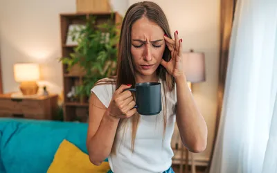 A woman holding her head in pain, illustrating a headache or migraine.