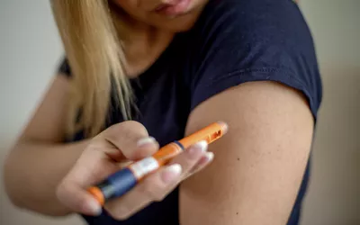 A woman using an insulin pen to administer a dose in her arm.