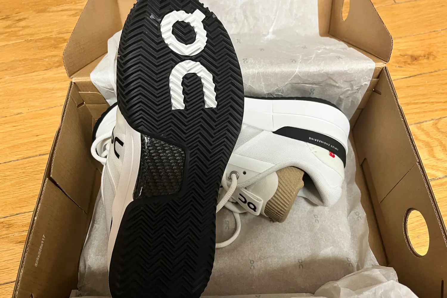 Close-up of the herringbone tread and carbon fiber plate on the sole of an On Running shoe.