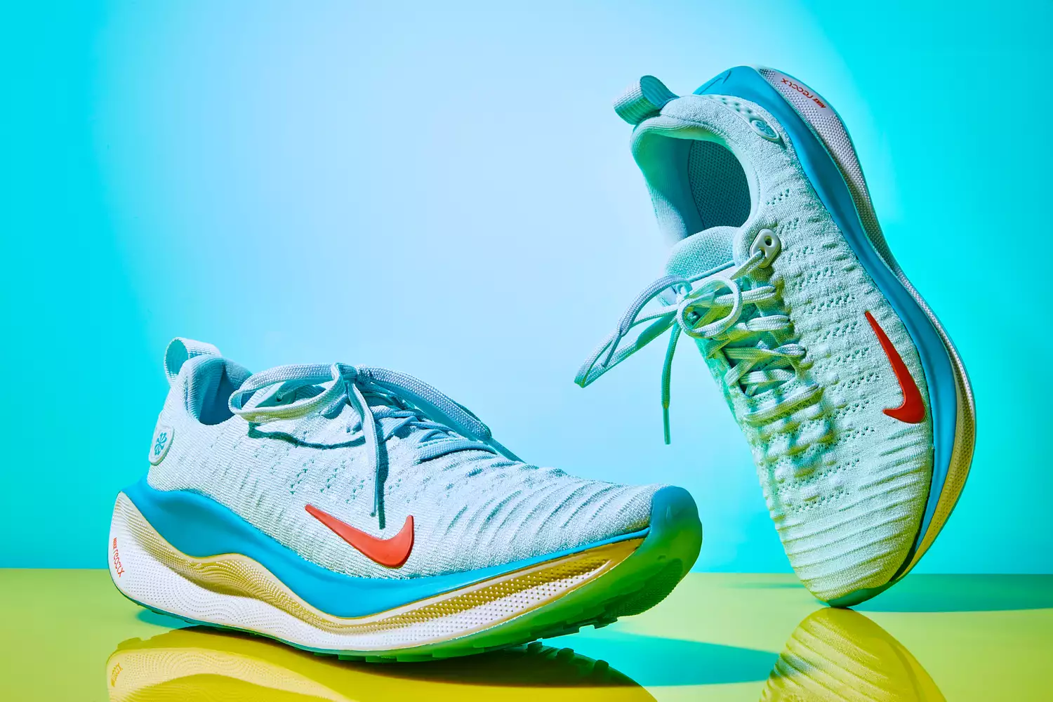 Side-profile of light blue Nike running shoes on a yellow reflective surface.