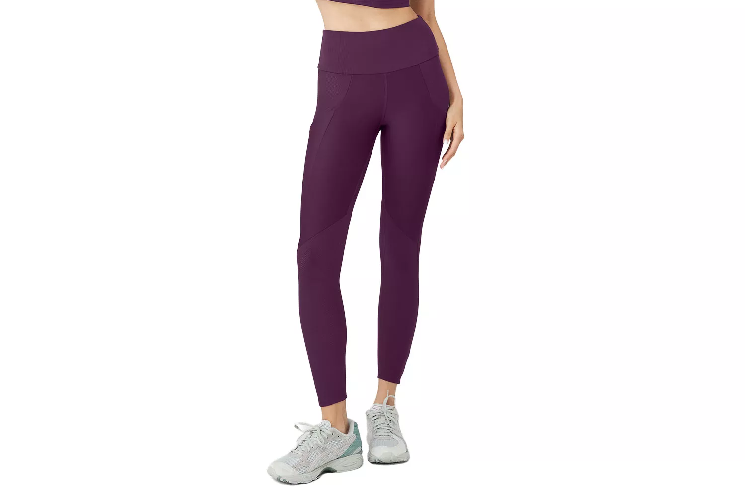 A woman modeling purple high-waisted leggings with functional side pockets.