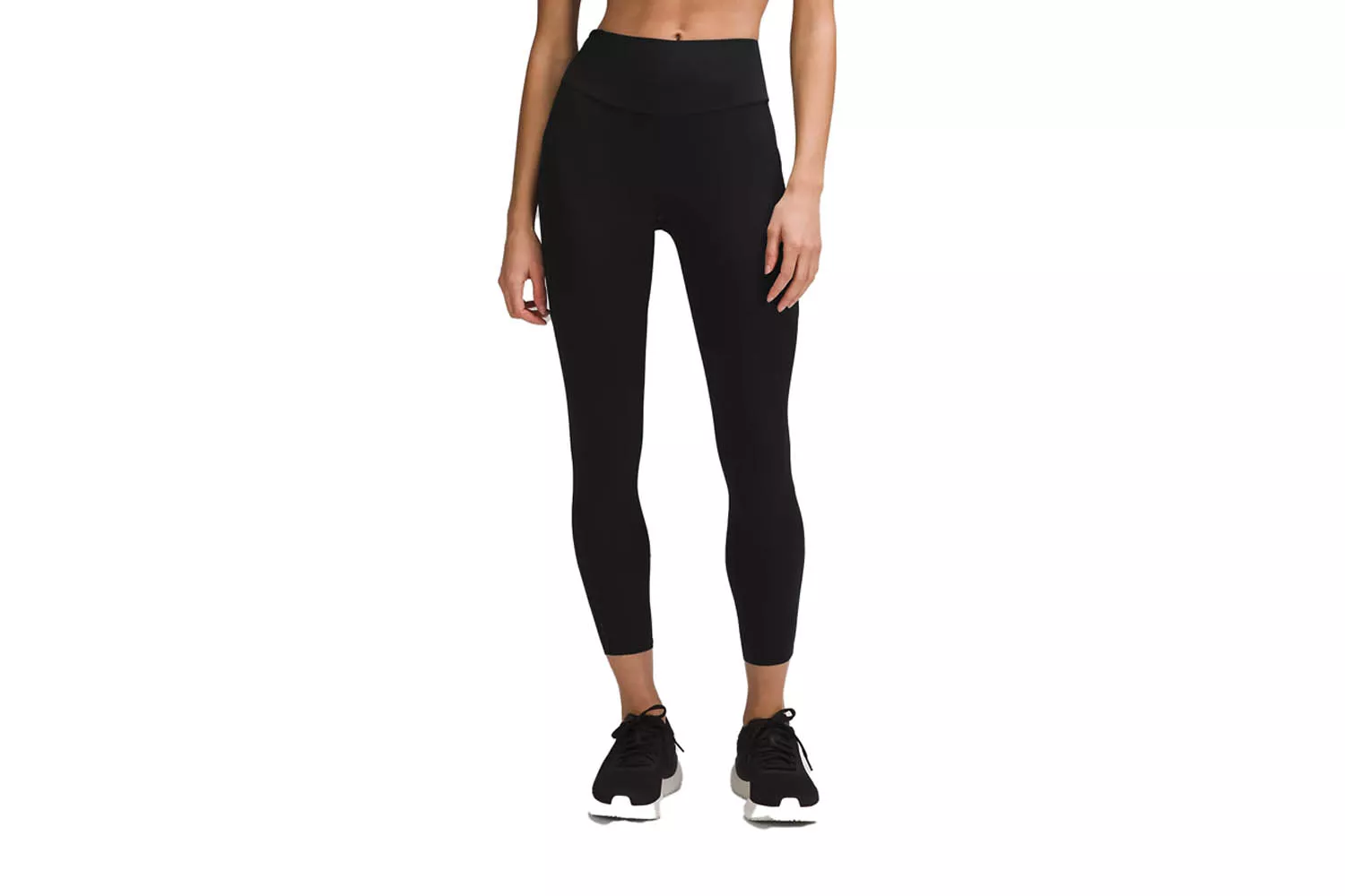 A woman modeling black high-rise athletic leggings that hit perfectly at the ankle.