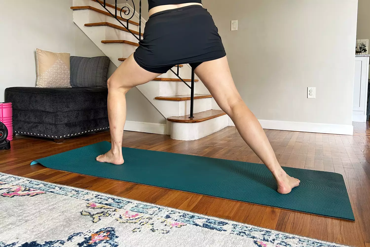 A woman performing a side lunge on a yoga mat wearing a black athletic skort.