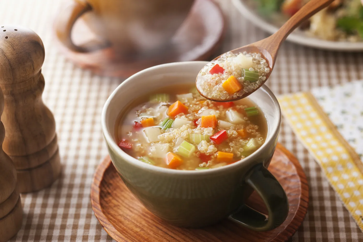 A close up view of a vegetable soup containing quinoa and chopped vegetables.