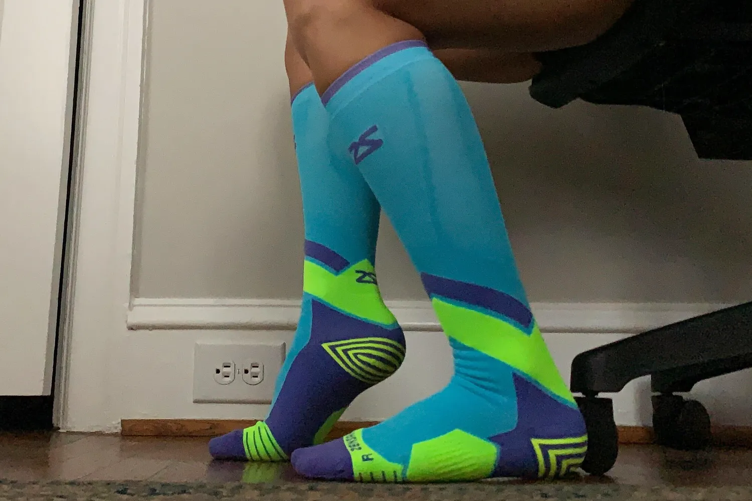 A person seated wearing Zensah Tech+ compression socks.