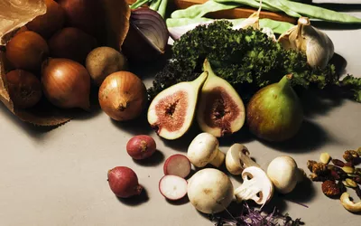 An assortment of fresh whole foods including mushrooms, kale, and radishes.