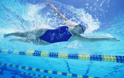 A swimmer performing a freestyle stroke in a pool, symbolizing active lifestyle and wellness.