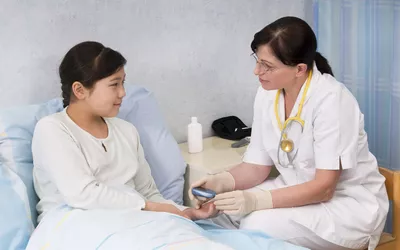 A medical professional in a clinical setting checking a patient's blood glucose levels.