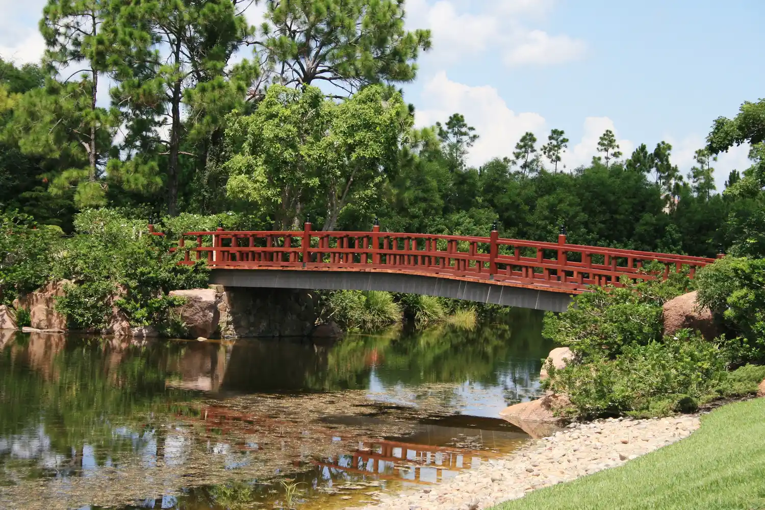 A serene wooden bridge crossing a waterway surrounded by lush tropical greenery at Morikami Gardens.
