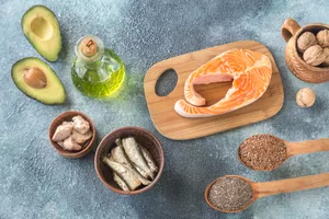 An arrangement of salmon, sardines, walnuts, and avocado representing omega-3 and vitamin-rich foods.