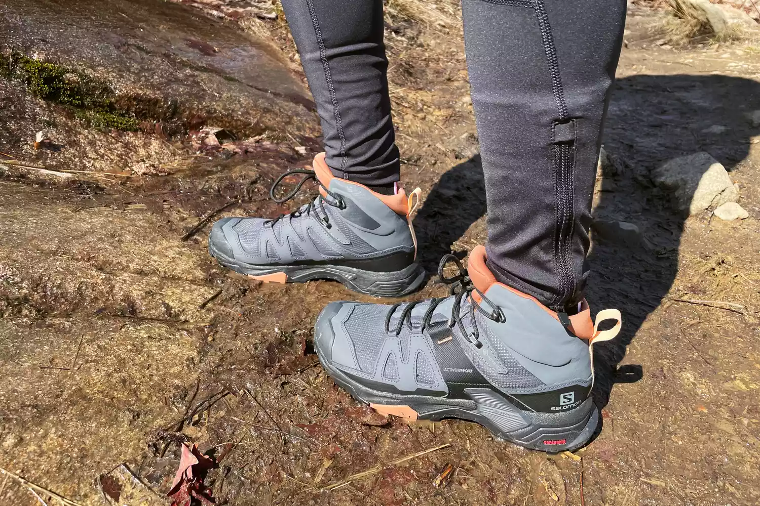 A hiker wearing Salomon X Ultra 4 Mid GTX boots on a wet, rocky trail.