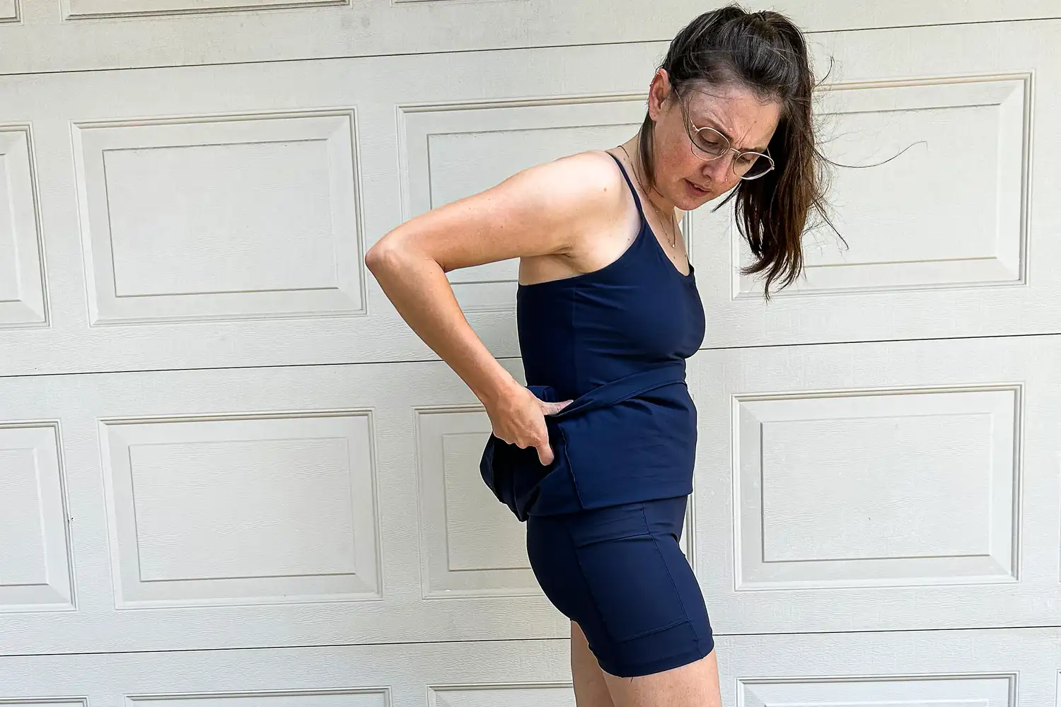 A person lifts the hem of the Outdoor Voices dress to show the built-in spandex shorts underneath.