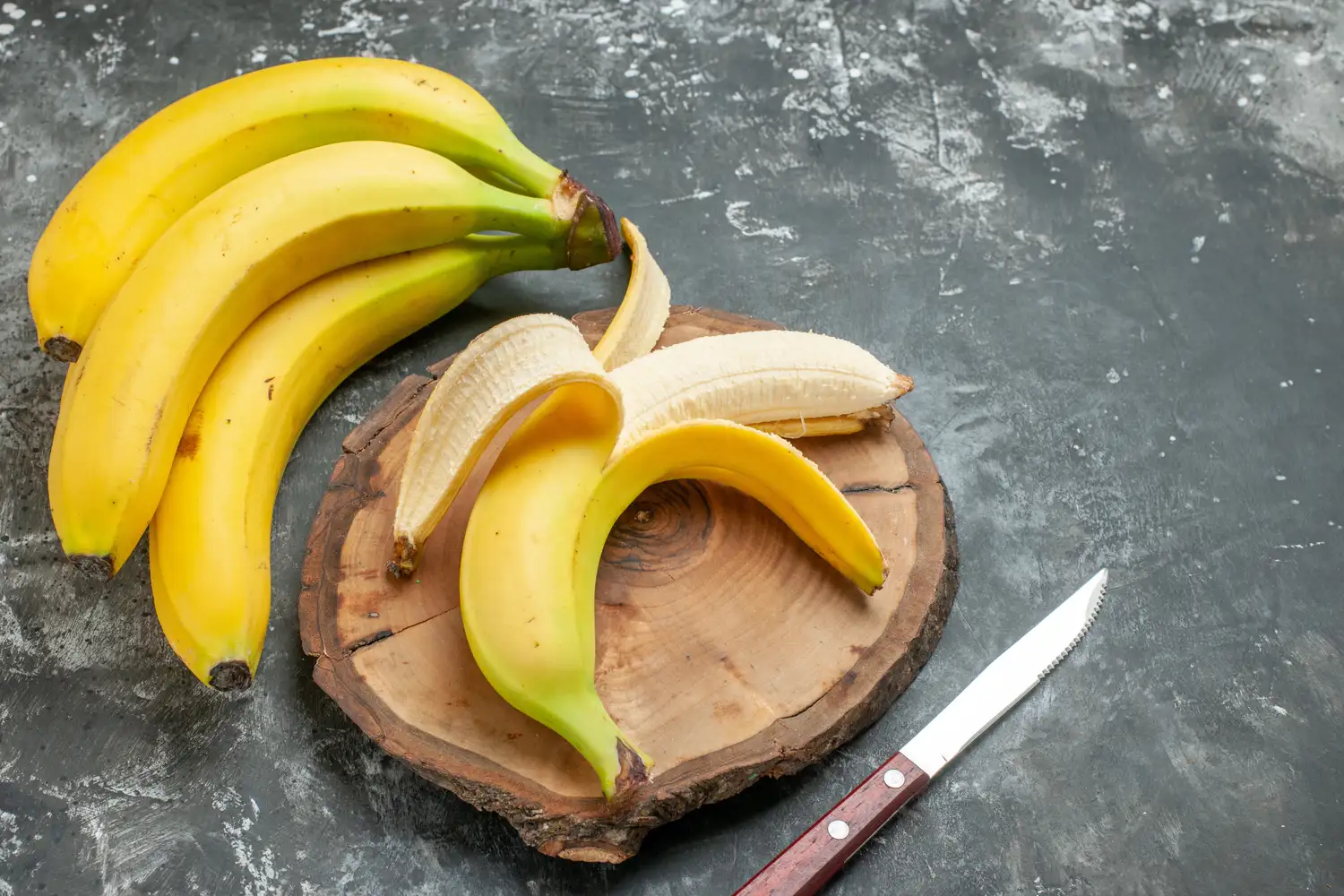 A bundle of yellow bananas on a wooden cutting board.
