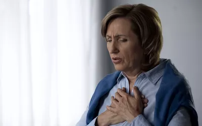 An individual clutching their chest in physical distress, representing acute medical symptoms.